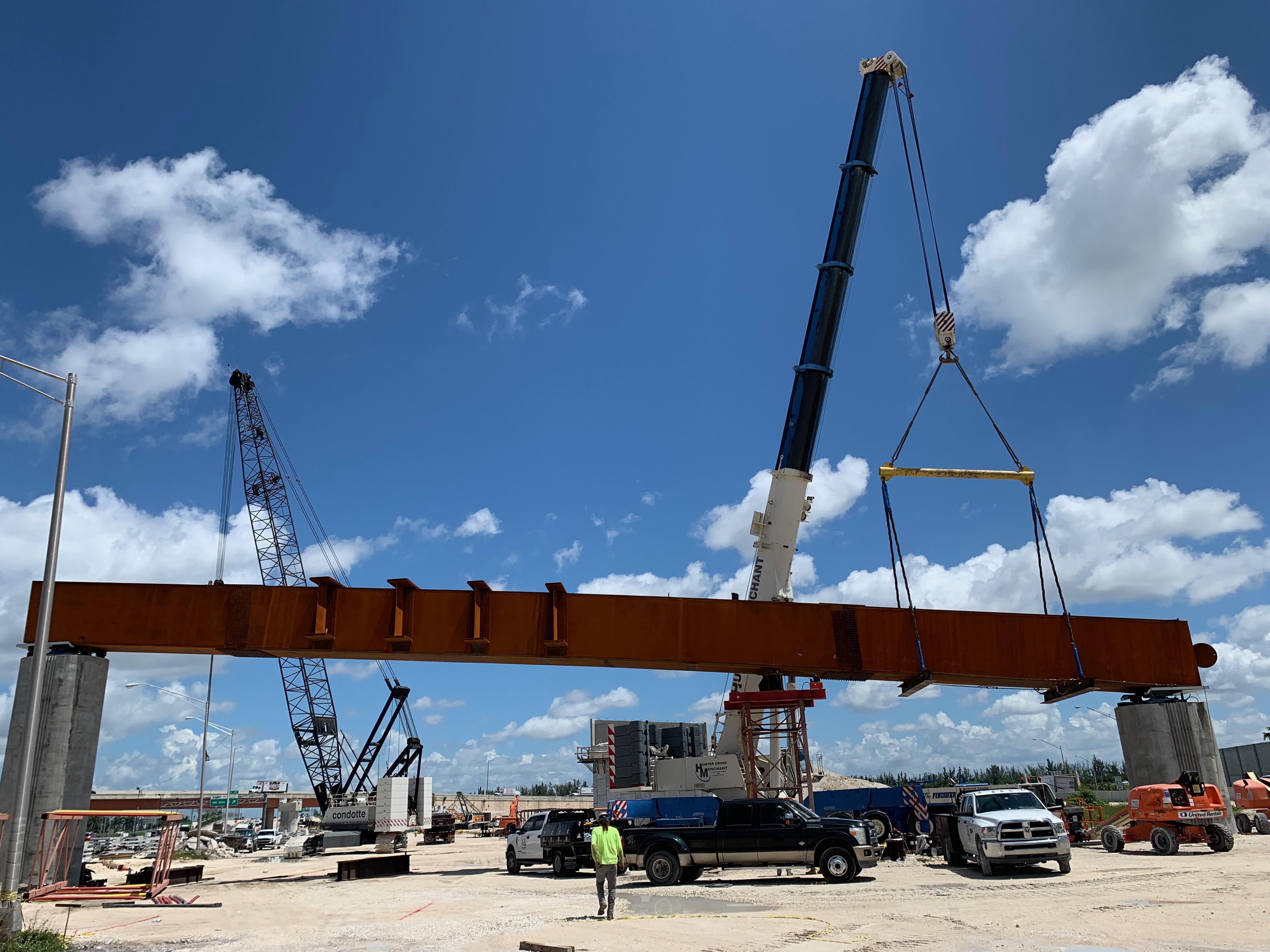 Steel bridge girder being placed by two cranes during construction