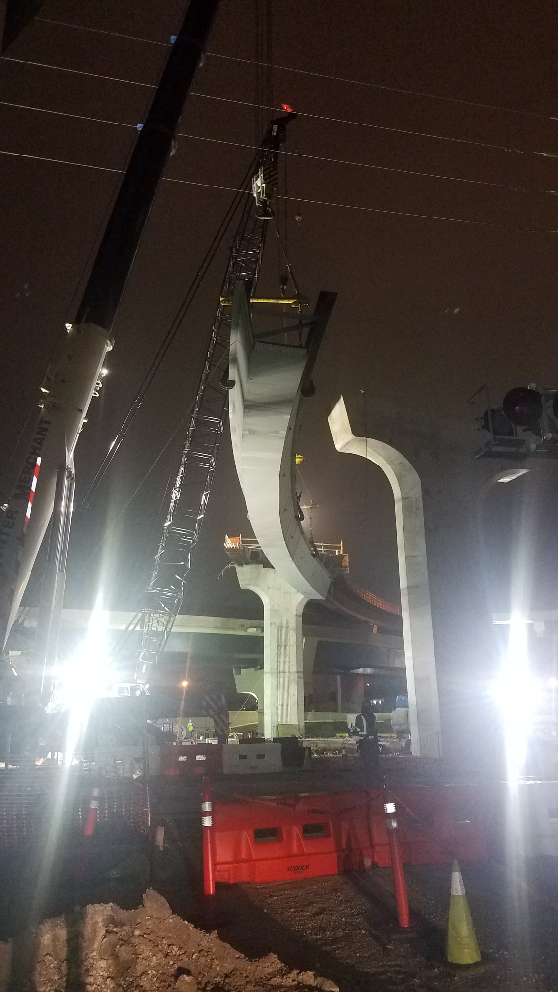 Curved precast tub girder being placed at night over a highway
